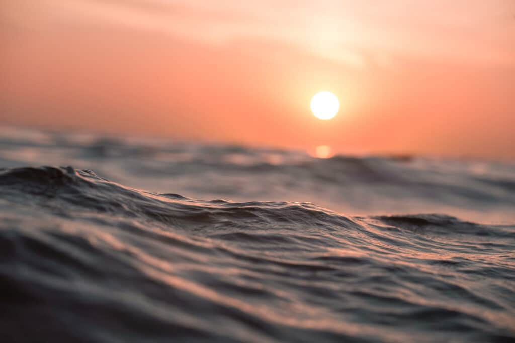 Vagues calmes au coucher du soleil évoquant la sérénité et la profondeur de la PNL dans la transformation personnelle.