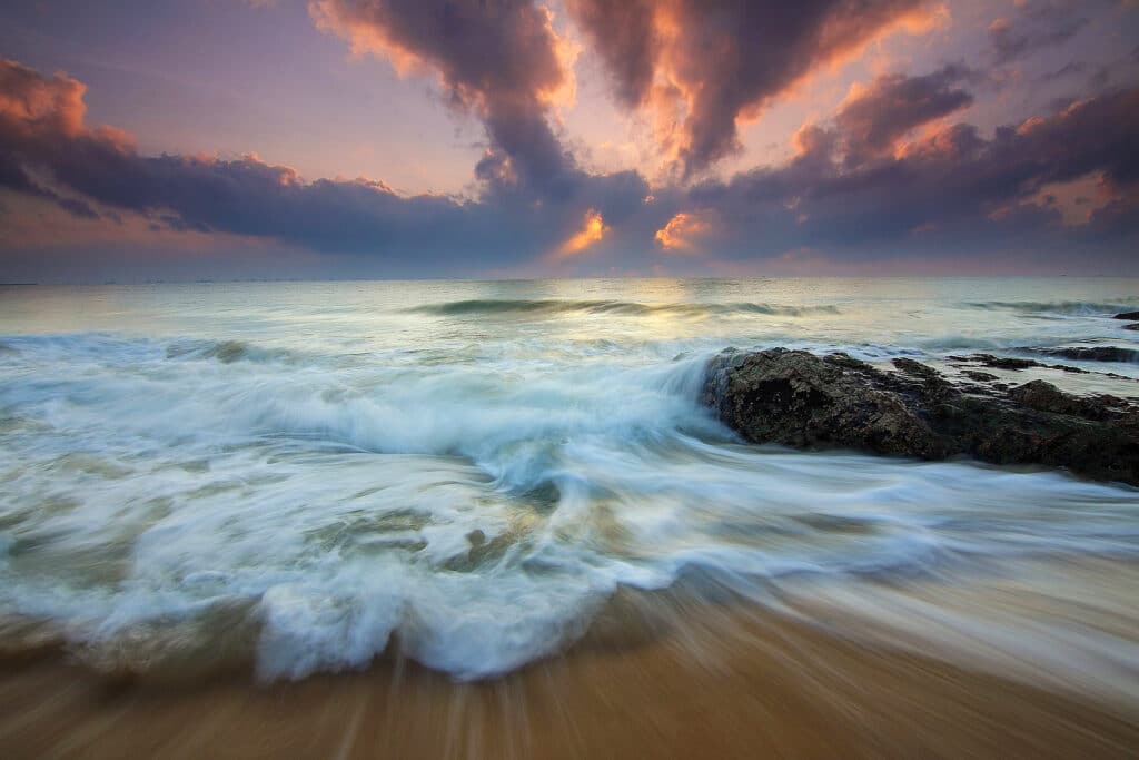 Vagues énergiques et coucher de soleil vibrant évoquant la force naturelle du magnétisme et le rééquilibrage des énergies.